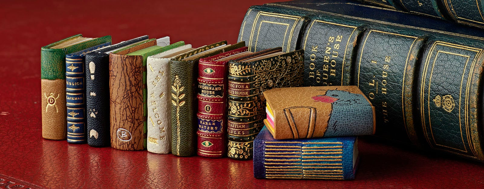 New miniature books created in celebration of 100 years of Queen Mary’s Dolls’ House. A selection of miniature books lined up next to regular sized book.